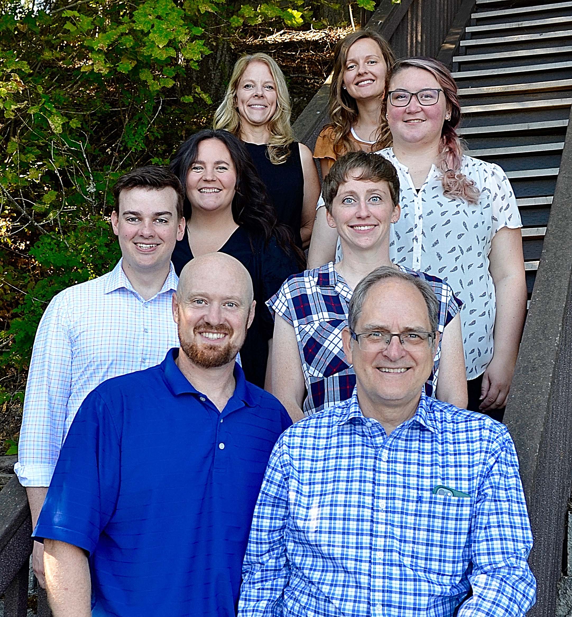 A group of people standing on stairs with trees in the background.